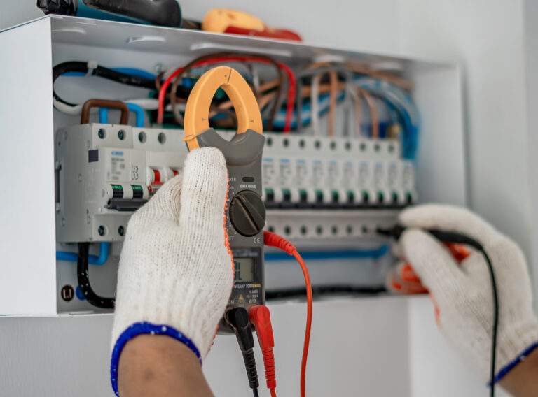 A man in gloves inspects an electrical panel while conducting a safety report for a property’s electrical installation.
